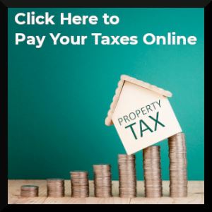 Miniature house on top of stacks of pennies with the word "Taxes"